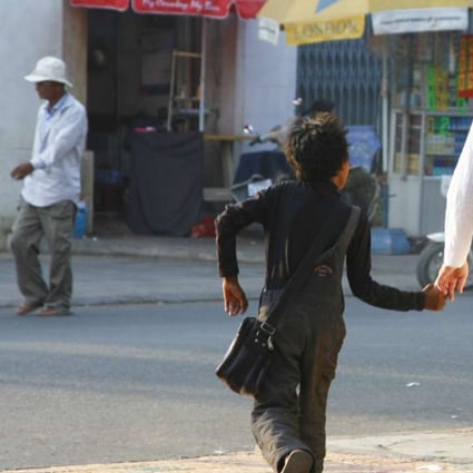 A middle-aged Western man walks hand in hand with a local boy in Phnom Penh. A report of this kind of suspicious behaviour is usually enough to convince Action Pour Les Enfants to begin an investigation. Photo: Courtesy of APLE Cambodia
