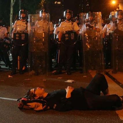 A protester lies down in the street in front of a row of police officers. Photo: K.Y. Cheng