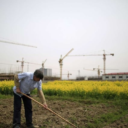A farmer tends to a field in front of a construction site in Shanghai. The push for unemployed people to consider a life in the countryside comes at a time when the nation is struggling to create jobs in the cities. Photo: Reuters
