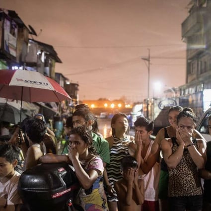 Residents near a crime scene where three alleged drug dealers were killed after a drug raid in a shanty community in Manila. Photo: AFP