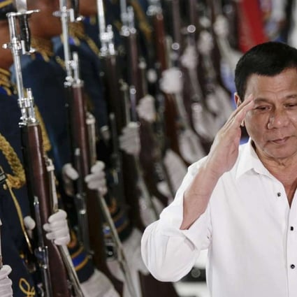 Philippine President Rodrigo Duterte reviews an honour guard on Tuesday during a departure ceremony at the Manila International Airport before departing on a trip to Cambodia and Singapore. Photo: EPA