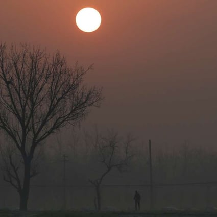 A man walks in the smog as the sun rises over Beijing on Monday. Photo: Reuters