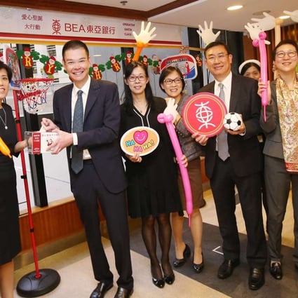 Executive director Adrian Li (third from left), general manager and head of HR Mimi Kam (second left) and other Bank of East Asia staff raise a cheer after a week of charity events. Photos: David Wong
