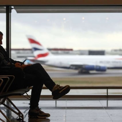 A passenger sits at a departure gate against a backdrop of a British Airways aircraft landing, at terminal 2 at London Heathrow Airport in London on December 23. Photo: Bloomberg