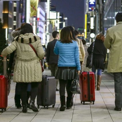 Chinese tourists carry suitcases packed with purchases during bulk buying, known as Bakugai, in central Tokyoin 2015. Photo: EPA