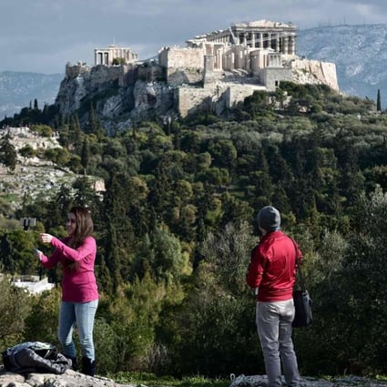 Tourists watch the Acropolis from the Pnyx hill in Athens, Greece. Photo: AFP