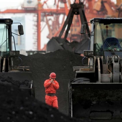 An employee walks between front-end loaders which are used to move coal imported from North Korea at Dandong port in Liaoning. Photo: Reuters