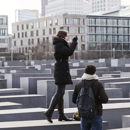 Visitors take photos while standing on the blocks of the Memorial to the Murdered Jews of Europe in Berlin last Thursday. Photo: EPA