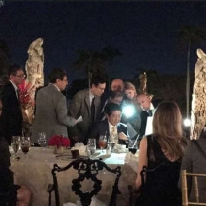 A photo posted on social media by a fellow diner shows aides crowding around Japanese Prime Minister Shinzo Abe, as he attempts to read documents by cellphone light, as he dines with Donald Trump at the Mar-a-Lago resort on Saturday night. The two leaders had just been told that North Korea had fired a missile towards Japan. Photo: Facebook / Richard DeAgazio