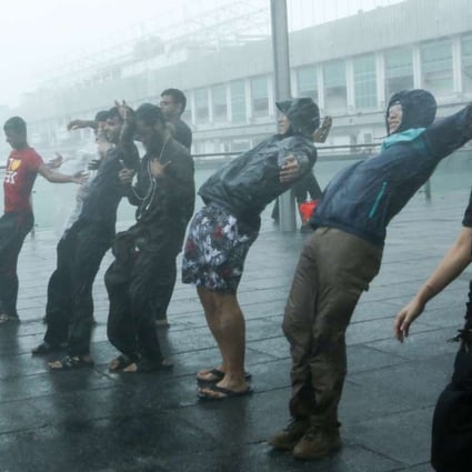 People brave the strong winds in Tsim Sha Tsui last October as Typhoon Haima hits Hong Kong. The consequences of global warming are not limited to extreme weather conditions or the increasing frequency and intensity of heat waves and cold spells that the media tends to focus on. Photo: Edmond So