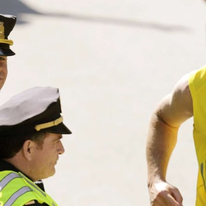 Actor Mark Wahlberg, left, dressed as a Boston Police officer, watches runners cross the finish line as he films a scene for his "Patriot's Day" movie about the 2013 Boston Marathon bombing. Photo: AP