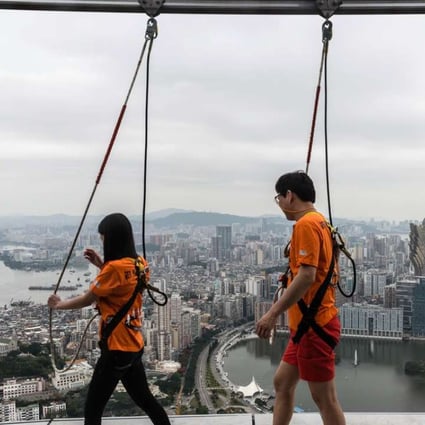 Tourists take part in a "sky walk" on the rim of the 61st floor of the Macau Tower in Macau. Photo: AFP