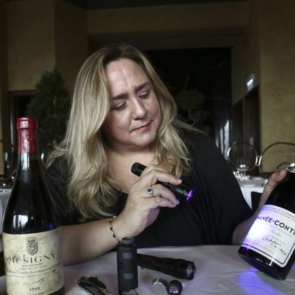 Maureen Downey shows how she uses a blue light to check the age of the paper used on labels, on a this bottle of fake Romanée-Conti. Photo: Jonathan Wong