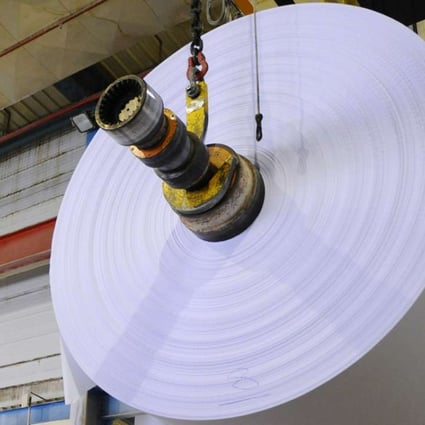 A worker inspects paper at a factory. Rising demand is pushing producer prices higher. Photo: AFP