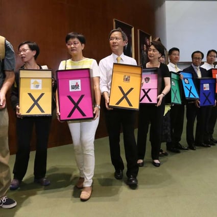 Pan-democrat lawmakers hold signs indicating their stance as they enter the Legislative Council chamber ahead of a debate on the electoral reform proposal, in Tamar on June 17, 2015. The reform package was rejected the following day. Photo: Sam Tsang