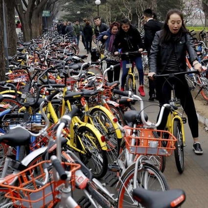People riding yellow bicycles from bike-sharing company Ofo try to pedal along a pavement crowded with bicycles from bike-sharing companies Ofo, Mobike and Bluegogo in Beijing last month. (March) Photo: AP