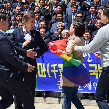 A supporter of the LGBT community carrying a rainbow flag approaches presidential candidate Moon Jae-in. Photo: EPA