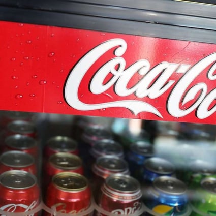 A Coca Cola sign is seen as Coke products are on display in a store as the company announces plans to cut 1200 corporate staff jobs. The announced changes come as the company battles a slide in soda sales which along with higher costs has lead to a 20 per cent drop in quarterly profit. Photo: AFP