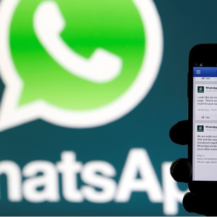 A WhatsApp logo is seen behind a phone that is logged on to Facebook. The popular messaging system was down worldwide for several hours on Wednesday. Photo: Reuters