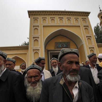 Uygur men stand outside the Id Kah Mosque after Friday prayers in Kashgar in July 2014. Photo: EPA