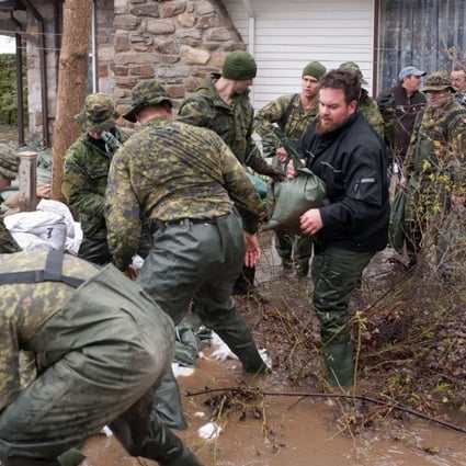 Canadian soldiers help residents of Pierrefonds after heavy flooding caused by unrelenting rain in Central and Eastern Canada on Sunday. Photo: AFP