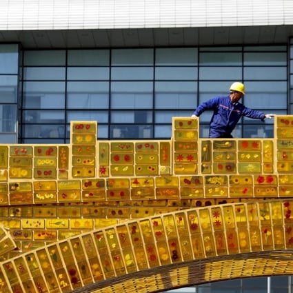 The “Belt and Road Initiative” uses free-trade agreements and infrastructure projects to create a modern Silk Road spanning some 65 countries. Pictured, a worker walks on a “Golden Bridge of Silk Road” structure on display outside the National Convention Centre in Beijing. Photo: AP