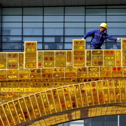 A worker walks on a 'Golden Bridge of Silk Road' structure on display outside the National Convention Centre, the venue for the Belt and Road Forum for International Cooperation, in Beijing. Photo: AP