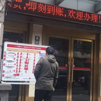A passerby looks at the advertisement of an Anbang Insurance Group's universal insurance policy and other wealth management products available at a China Guangfa Bank outlet in Shanghai. Photo: Maggie Zhang