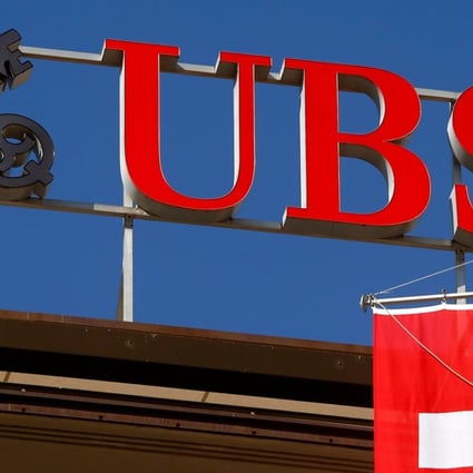 Switzerland's national flag flies under the logo of Swiss bank UBS in Zurich, Switzerland. Singapore GIC Private Ltd is selling part of its stake in the bank. Photo: Reuters