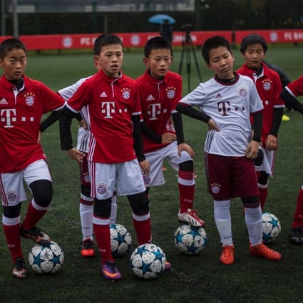 Chinese boys in Bayern Munich jerseys take part in a practise session after the opening ceremony of Bayern's office in Shanghai on March 22, 2017. AFP PHOTO / Johannes EISELE
