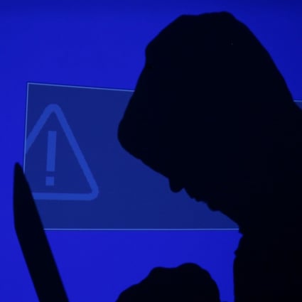 A hooded man holds a laptop computer as a blue screen with an exclamation mark is projected on him in this illustration picture taken on May 13, 2017. Capitalising on spying tools believed to have been developed by the US National Security Agency, hackers staged a cyber assault with a self-spreading malware that has infected tens of thousands of computers in nearly 100 countries. Photo: Reuters