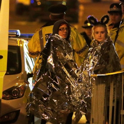 Two women wrapped in thermal blankets stand near the Manchester Arena. Photo: Reuters