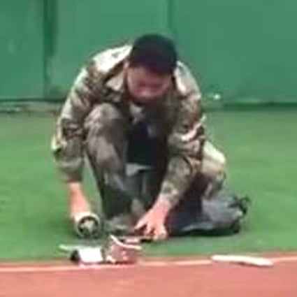 A man in military uniform takes a hammer to a confiscated phone in this screenshot from an online video. Photo: Handset