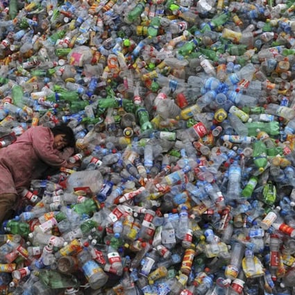 A labourer rests on piles of plastic bottles at a recycling centre in Zhejiang province. Photo: Reuters