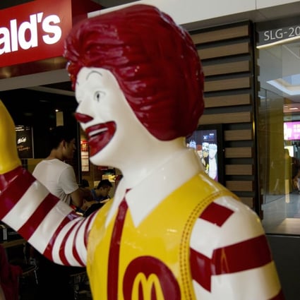 A customer walks past a statue of Ronald McDonald outside a McDonald's restaurant in Beijing. The fast food giant is targeting smaller mainland Chinese cities as part of a five year expansion plan. Photo: AP