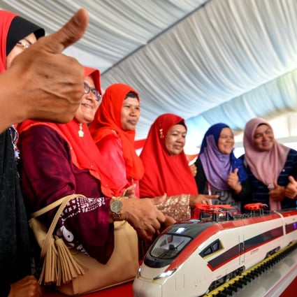 Women pose with a model train during the ground breaking ceremony for the East Coast Rail Link project in Malaysia, on August 9. The scheme is one of many being developed under China’s “Belt and Road Initiative”. Photo: Xinhua