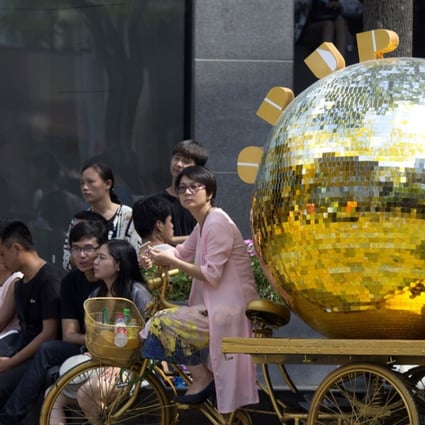 A woman sits on a tricycle painted gold and used as a marketing gimmick in Beijing on August 8, 2017. China's demand for the precious metal rose 10 per cent to 545 tonnes during the first six months of 2017. Photo: AP