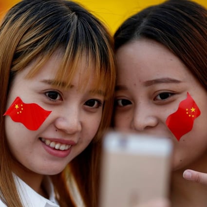 Girls wearing Chinese flags on their cheeks take pictures as people gather in Tiananmen Square to celebrate National Day marking the 67th anniversary of the founding of the People's Republic of China, in Beijing October 1, 2016. Photo: Reuters
