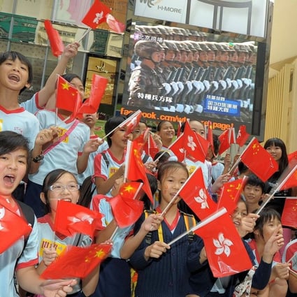 This handout photo from Hong Kong PR company Wasabi Creation shows mainland Chinese children cheering with Hong Kong and Chinese flags as they watch the broadcast of the military parade in Beijing, at the World Trade Centre building in Hong Kong on October 1, 2009. Photo: AFP