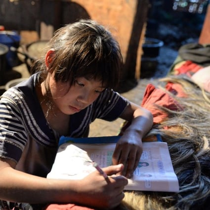 A file picture of a girl in a mountainous area of Yunnan province doing her school homework on her bed in Mukeji village. Photo: Xinhua