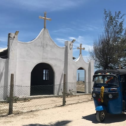 A three-wheeler passes in front of a Catholic church in Nainativu. Photo: Paul Niel