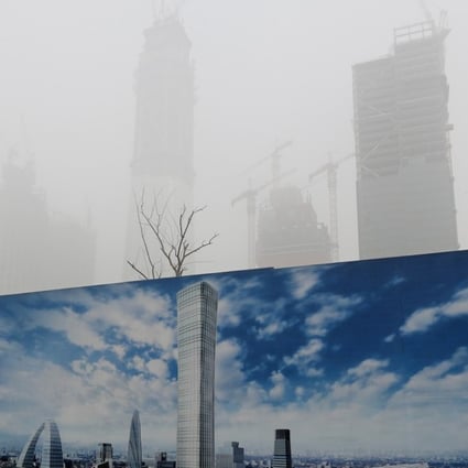 A construction site hoarding featuring a blue sky contrasts with smog in Beijing in December last year. Photo: AP