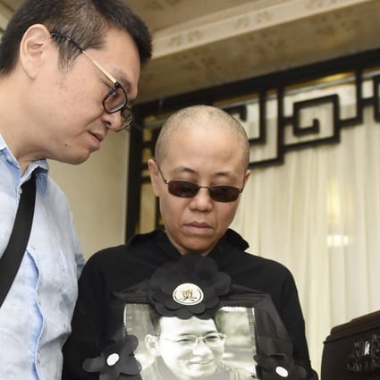 Liu Xia (centre), wife of late Nobel Peace Prize winner Liu Xiaobo, holds a portrait of her husband during his funeral in Shenyang in July. Supporters said they contacted her on Saturday. Photo: AP