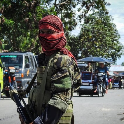 A Moro Islamic Liberation Front (MILF) rebel with face covered, along with a government soldier man a mobile check point in Datu Salibo town, Maguindanao province, in southern island of Mindanao. Photo: AFP