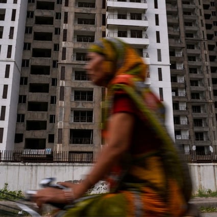 An Indian cyclist rides past incomplete residential flats in Greater Noida, southeast of New Delhi. Real estate accounts for about US$19.5 billion of stressed loans in India. Photo: AFP