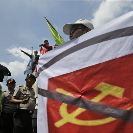 A man carries a banner of defaced communist symbol during a protest in Jakarta last year against the discussion of anti-communist massacres in 1965. Photo: AP