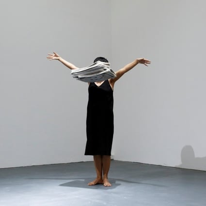 Performance artist Yi Fei drops a pile of newspapers as she performs her piece No News at the OPEN international performance art festival. Photo: Reuters