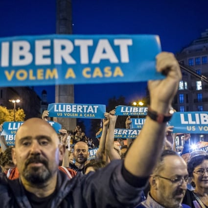 Protesters hold up banners reading “Help Catalonia” during a candlelight vigil to demand the release of imprisoned separatist leaders Jordi Sanchez, head of the Catalan National Assembly, and Jordi Cuixart, head of the Omnium Cultural association, in Barcelona, Spain, on October 17. Photo: Bloomberg
