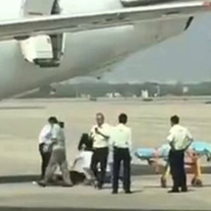 The woman is treated on the tarmac after falling out of the aircraft. Photo: Sina.com