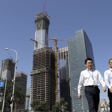 Chinese people walk by a construction site at the Central Business District in Beijing. By downplaying hard economic targets, future growth will slow down but be more balanced and sustainable. Photo: AP